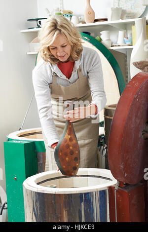 Reife Frau im Töpferatelier Vase im Brennofen feuern Stockfoto