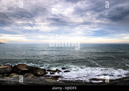 Meerwasser läuft über die Felsen am Meeresufer. Große Felsen, viele Wolken und den Horizont auf eine wunderschöne Seenlandschaft, wunderbare Szene in Morro Das Pedras, Stockfoto