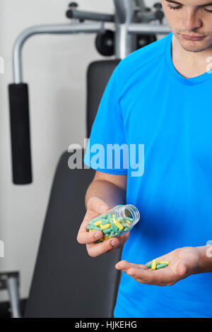 Junger Mann In der Turnhalle, die Einnahme von Tabletten Stockfoto