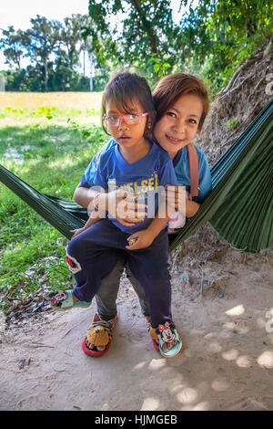 Eine teenage kambodschanische Mutter sitzt auf einer Hängematte mit ihrer Tochter in Banteay Srei, Kambodscha. Stockfoto