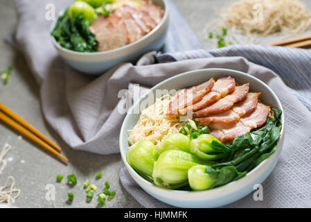 köstliche Eiernudeln mit roten Schweinefleisch und Gemüse in der Schale Dekoration mit Essstäbchen am Tisch, thailändischen, selektiven Fokus. Stockfoto