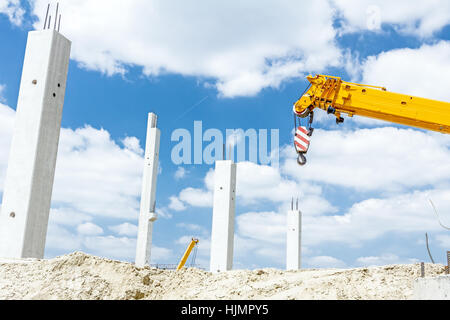 Kranarm ist bereit für den Betrieb, Montage Betonsäulen auf neue Gebäude. Stockfoto