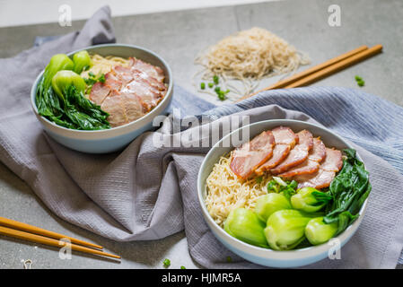 köstliche Eiernudeln mit roten Schweinefleisch und Gemüse in der Schale Dekoration mit Essstäbchen am Tisch, thailändischen, selektiven Fokus. Stockfoto