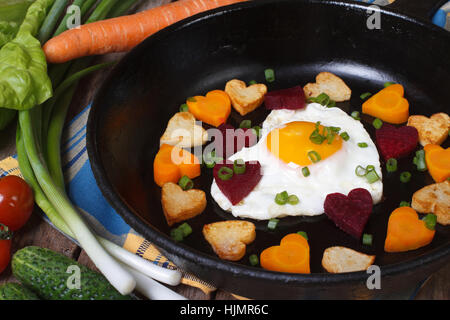 Gebratene Kartoffeln, Karotten, Rüben und Ei in Form eines Herzens auf der Pfanne Stockfoto