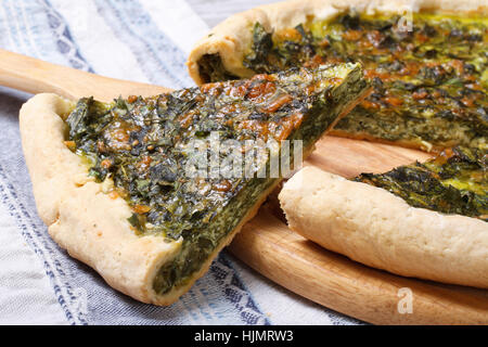 Stück Kuchen mit Grün gefüllt Spinat, Eiern und Käse hautnah auf Holzbrett Stockfoto