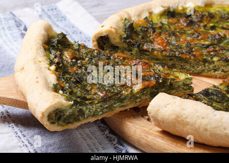 Stück Kuchen mit Grün gefüllt Spinat, Eiern und Käse hautnah auf Holzbrett. horizontale Stockfoto