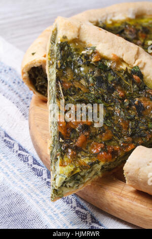 Stück Kuchen mit Grün gefüllt Spinat, Eiern und Käse hautnah auf Schneidebrett. vertikale Stockfoto