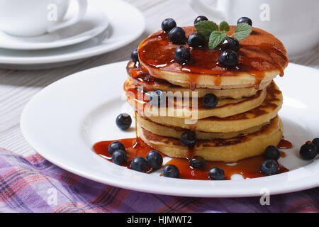 Amerikanische Pfannkuchen mit Blaubeeren und Ahornsirup auf einem weißen Teller horizontale Stockfoto