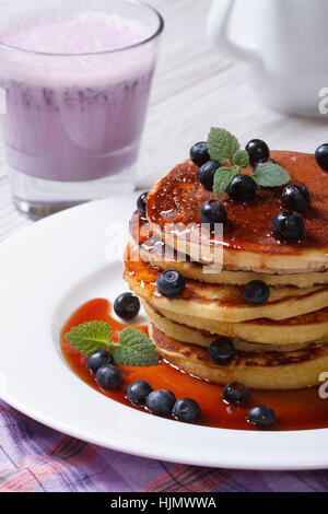 Heidelbeer-Pfannkuchen mit Ahornsirup und eine cocktail Nahaufnahme auf dem Tisch getränkt. vertikale Stockfoto