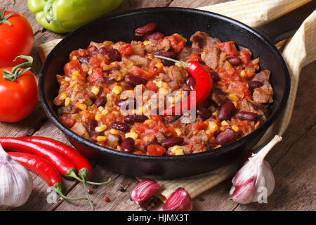 Chili Con Carne Nahaufnahme in einer Pfanne auf einem hölzernen Hintergrund mit den Zutaten. horizontale Stockfoto