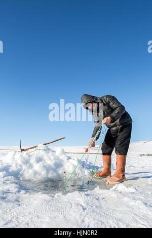 Ardahan, Türkei - 14. Januar 2017: Fischer angeln mit Fischnetz auf zugefrorenen Cildir See in Ardahan Stadt der Türkei am 14. Januar 2017. Stockfoto