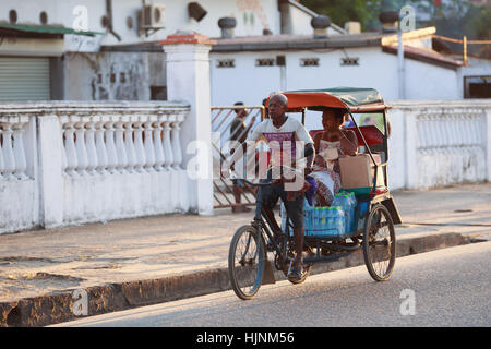 TOAMASINA, Madagaskar - 17. Oktober 2016: Traditionelle Rikscha Fahrrad mit madagassischer Völker in Madagaskar zweitgrößte Stadt Toamasina. Gewöhnliche str Stockfoto