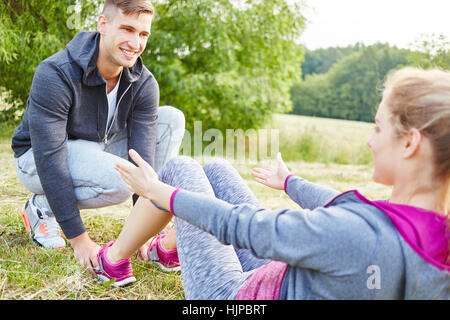 Arbeit Frau und Mann hilft ihr mit sit-ups Stockfoto