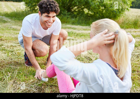 Junger Mann hilft Frau mit Sit-up Training Übung Stockfoto