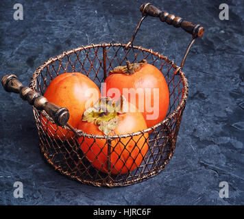 Ernte reif Kaki in stilvollen Metallkorb Stockfoto