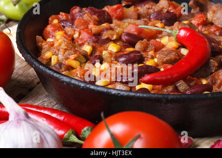 Mexikanisches Chili Con Carne Nahaufnahme in einer Pfanne auf einem hölzernen Hintergrund mit den Zutaten. horizontale Stockfoto