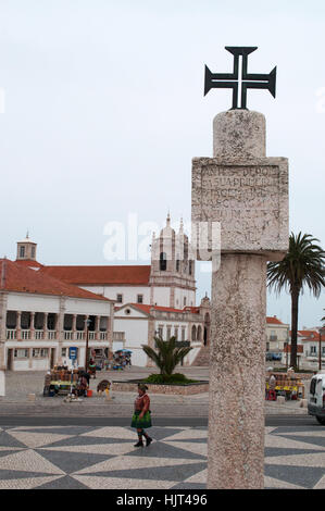 Ein Kreuz auf einer Spalte in den wichtigsten Platz Sitio, die alte Nachbarschaft von Nazare, mit Ansicht der Kirche unserer lieben Frau von Nazare Stockfoto