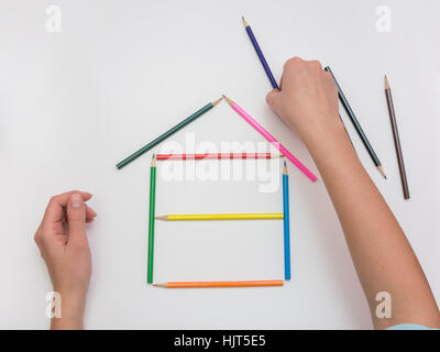 Die Hände von Frauen bauen ein Holzhaus aus Bleistiften Stockfoto