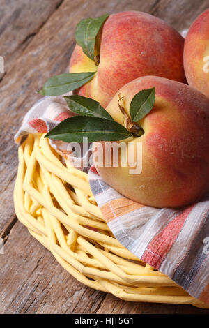 Frische saftige Pfirsiche in einem Korb auf den Tisch Closeup vertikale. Stockfoto