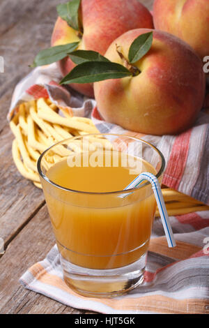 Duftende Pfirsichsaft und Früchte in einem Korb auf dem Tisch vertikal Stockfoto