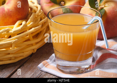 Pfirsichsaft in Glas Nahaufnahme auf einem Tisch auf einem Hintergrund von Obst. horizontale Stockfoto