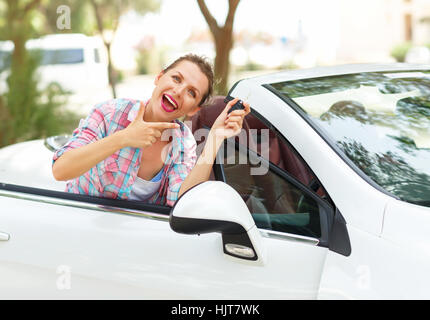 Junge Frau in der Nähe ein Cabrio mit Schlüssel in der Hand - Konzept für den Kauf eines Gebrauchtwagens oder einen Mietwagen Stockfoto