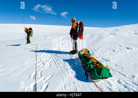 Eis-Führer einen Schlitten zu schleppen, da sie über eine Gletscherspalte an den Hängen des Mount Erebus in der Antarktis Wanderung. Stockfoto