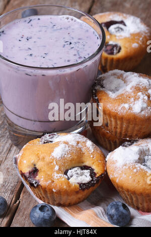 Blaubeer-Muffins und einen Milchshake mit Beeren auf Holztisch Nahaufnahme vertikal Stockfoto