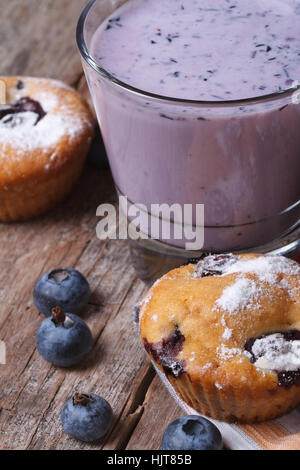 Muffins mit Heidelbeeren und Milch cocktail mit Beeren auf Holztisch Nahaufnahme vertikal Stockfoto