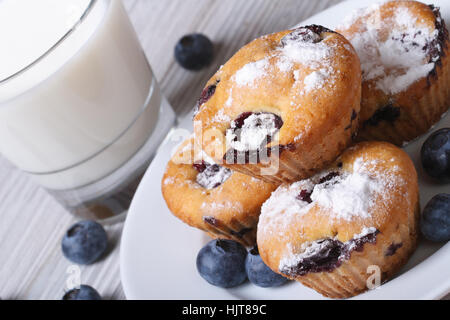 Muffins mit Heidelbeeren auf einem weißen Teller und Milch Closeup auf Holztisch. horizontale Stockfoto