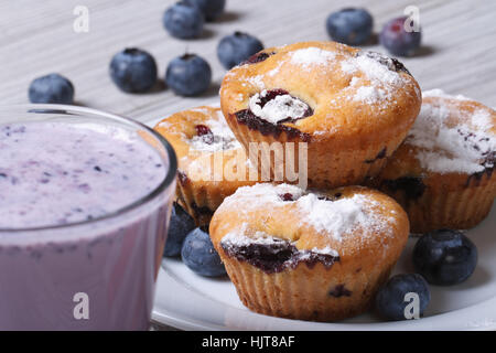 Blaubeer-Muffins auf einem weißen Teller und einen Milchshake Closeup auf einem Holztisch. horizontale Stockfoto