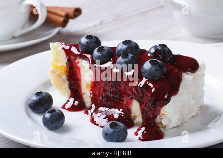 Käsekuchen mit Heidelbeeren auf weißen Teller Closeup und Kaffee auf dem Tisch horizontal Stockfoto