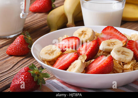 Müsli mit frischen Erdbeeren und eine Banane auf den Tisch und Milch in einen Krug. horizontale Stockfoto