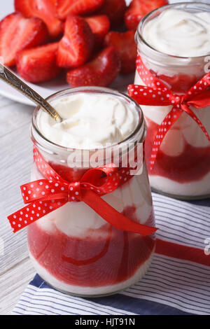 Joghurt mit Erdbeeren in ein Glas mit einer Nahaufnahme der Löffel auf dem Tisch vertikal Stockfoto