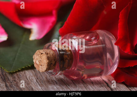 Öl aus Rosenblüten in einer Flasche auf einem floralen Hintergrund. Horizontale Nahaufnahme Stockfoto