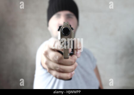 die Waffe im Vordergrund in der Hand des Angreifers Stockfoto