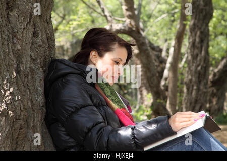 Mädchen-Lesebuch von einem Baum Stockfoto