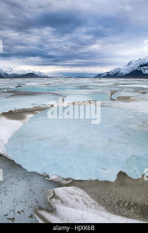 Große Eisbrocken durchscheinend auf gefrorenem Wasser mit Schnee und geblasenen Sand im Südosten Alaskas nahe Haines im Chilkat Inlet an einem stürmischen Tag. Stockfoto