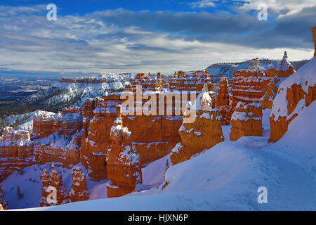 Die späte Nachmittagssonne spritzt über verschneite Hoodoos entlang der Navajo Loop Trail, Utah USA Bryce-Canyon-Nationalpark. Stockfoto