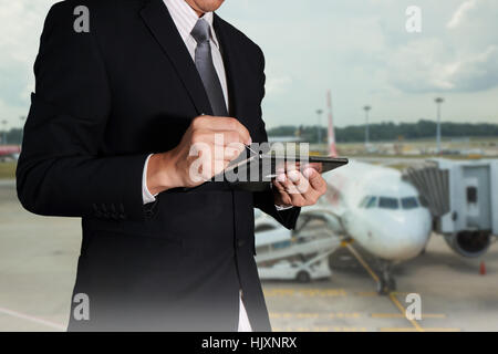 Geschäftsmann mit dem Tablet auf unscharf abstrakte Flughafen Hintergrund als Kommunikations-und Transport. Stockfoto