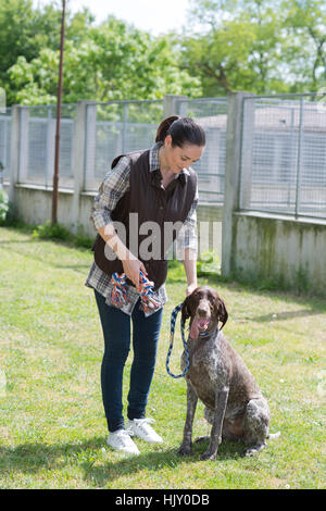 engagierte Mädchen Ausbildung Hund im Zwinger Stockfoto