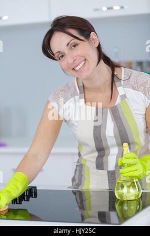 lächelnde Frau Reinigung Möbel in Küche Stockfoto