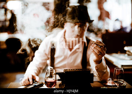 Gangster sitzt und raucht eine Zigarre durch Rauch Stockfoto