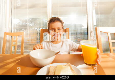 Fröhlicher Junge mit Glas mit Orangensaft Stockfoto