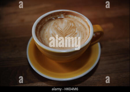 Milchkaffee in einer gelben Schale mit Musterdesign Stockfoto