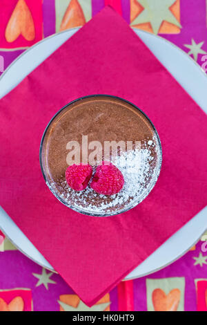 Dekadente hausgemachte Schokolade-Mousse mit frischen Himbeeren auf einer roten Serviette Stockfoto