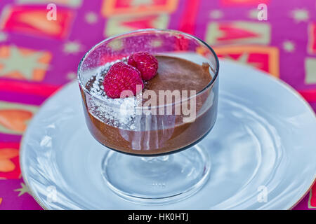 Dekadente hausgemachte Schokolade-Mousse mit frischen Himbeeren auf einer roten Serviette Stockfoto