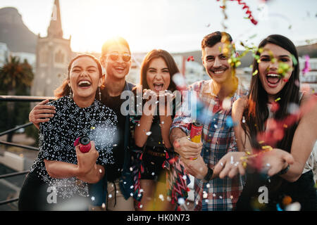 Gruppe von Freunden genießen Partei und werfen Konfetti. Freunde, die Spaß an Party auf dem Dach. Stockfoto