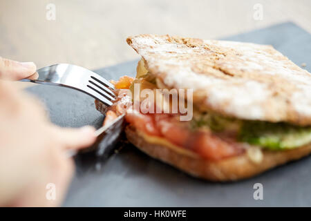 Person essen Lachs Panini Sandwich Restaurant Stockfoto