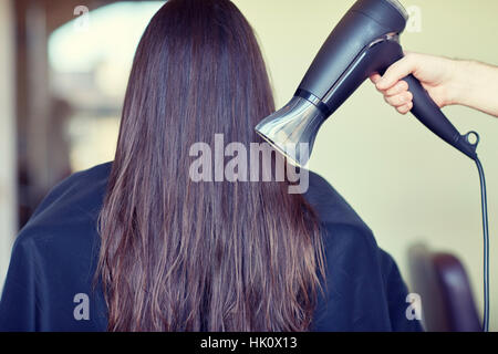 Stylist Hand mit Ventilator trocknet Frau Haare im salon Stockfoto